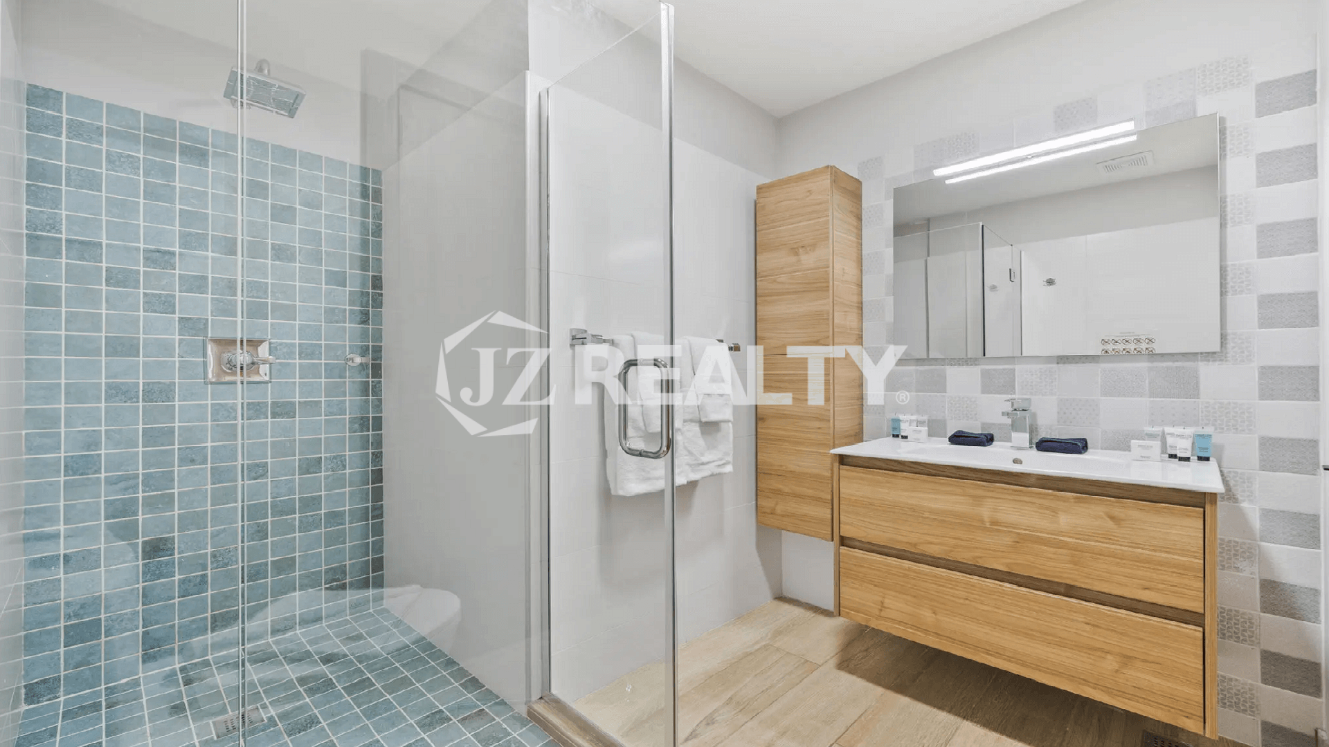Modern luxury bathroom at Porta al Sole Townhome in Aruba with wooden vanity and light blue/white mosaic tiled walk-in shower.