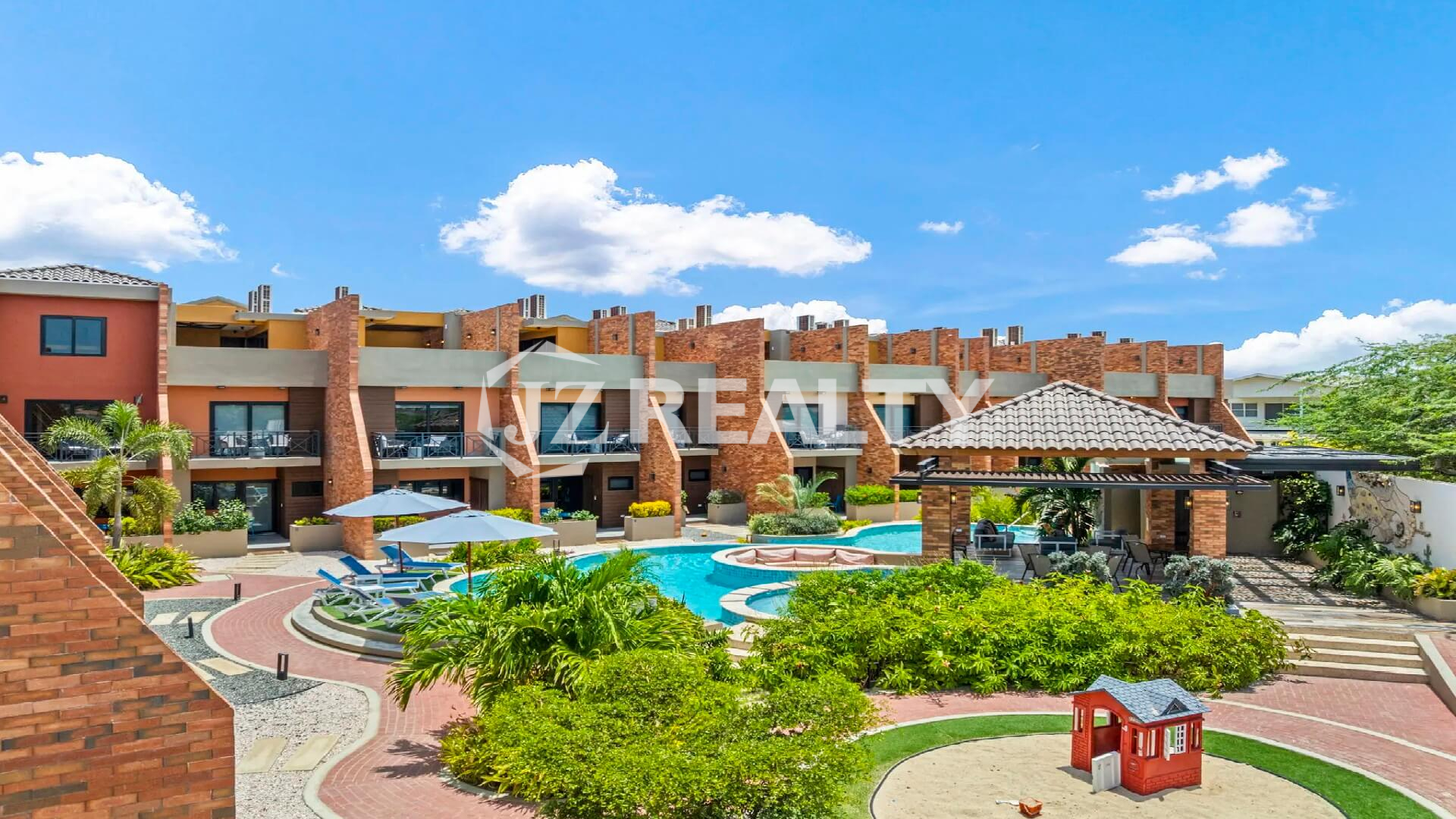 Aerial view of the Porta al Sole Townhouses surrounding the central community pool, lush landscaping, and the children's sandbox play area.