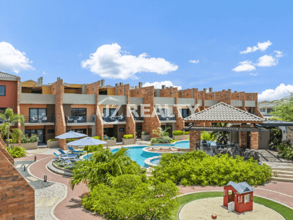 Aerial view of the Porta al Sole community buildings, complex pool, tropical landscaping, and a small children's play area.