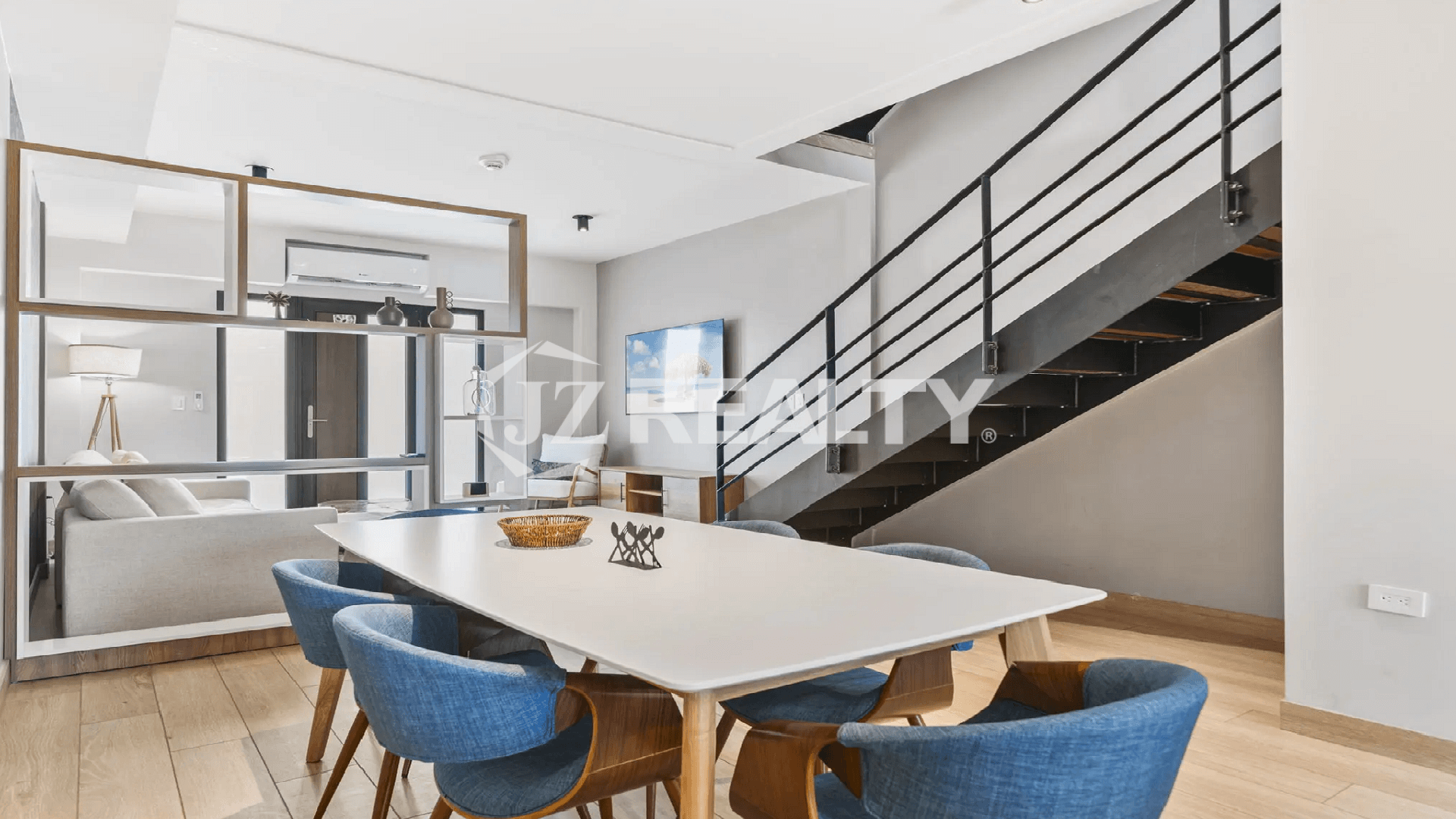Modern dining area at Porta al Sole with a white table, blue upholstered chairs, and a contemporary open-riser staircase leading to the upper floors.