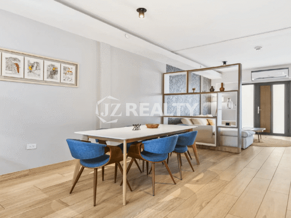 Dining room perspective in a Porta al Sole unit, showing the open shelving divider separating the space from the light-colored living room sofa.