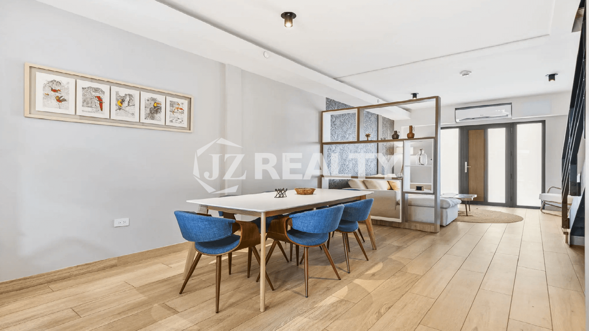 Dining room perspective in a Porta al Sole unit, showing the open shelving divider separating the space from the light-colored living room sofa.