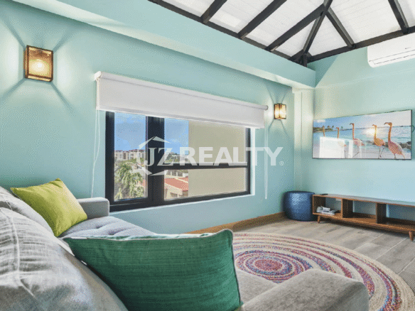 Upper-level family room/bonus room at Porta al Sole with vibrant teal walls, a vaulted ceiling, a large window, and a TV showing flamingos (Aruba wildlife).