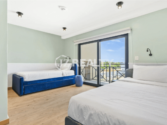 Second guest bedroom in a Porta al Sole condo, Aruba, with light mint green walls, twin beds, and a glass door leading to a small balcony.
