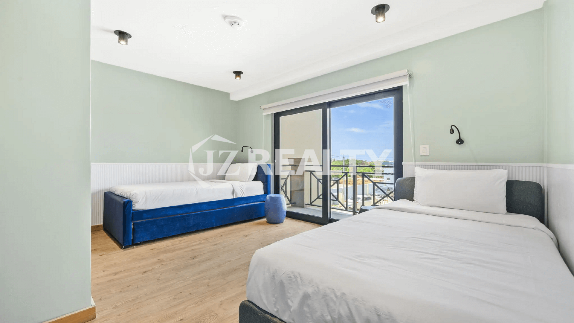 Second guest bedroom in a Porta al Sole condo, Aruba, with light mint green walls, twin beds, and a glass door leading to a small balcony.