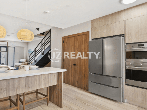 Modern kitchen design at Porta al Sole, showing stainless steel built-in appliances, a large refrigerator, and light wood-grain kitchen cabinetry.