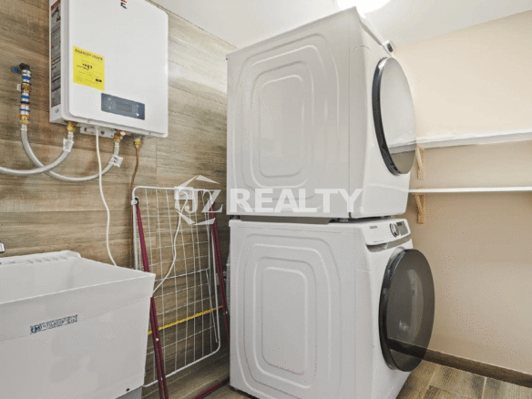 Dedicated laundry room in the Porta al Sole townhome featuring a stacked washer and dryer unit, utility sink, water heater, and storage shelves.