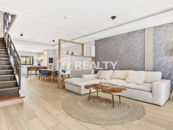 View of the open layout at Porta al Sole connecting the living room, dining area, and kitchen, featuring a stylish staircase and accent wall.