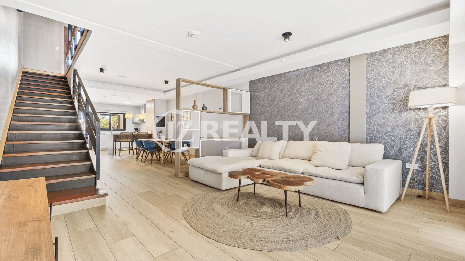 View of the open layout at Porta al Sole connecting the living room, dining area, and kitchen, featuring a stylish staircase and accent wall.