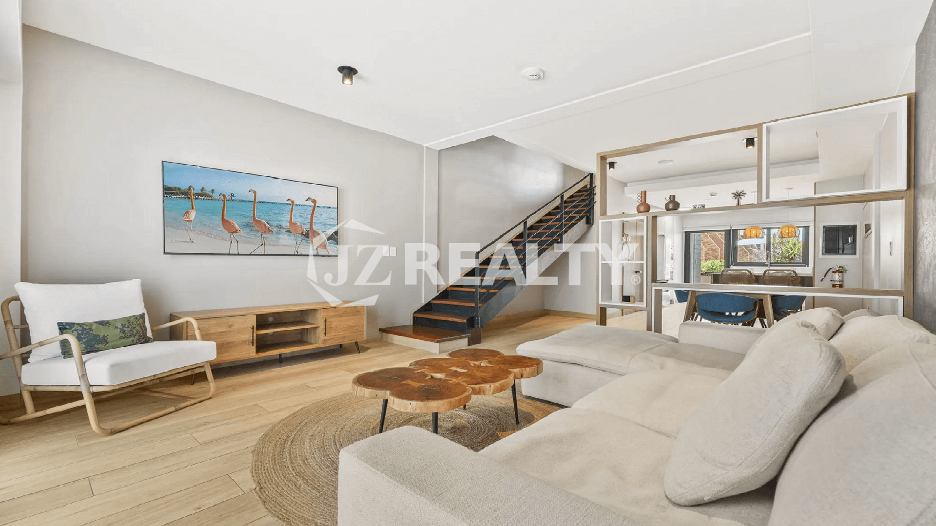 Bright, open-concept living room on the main floor of a Porta al Sole townhome, with a staircase, modern sectional sofa, and a natural wood coffee table.