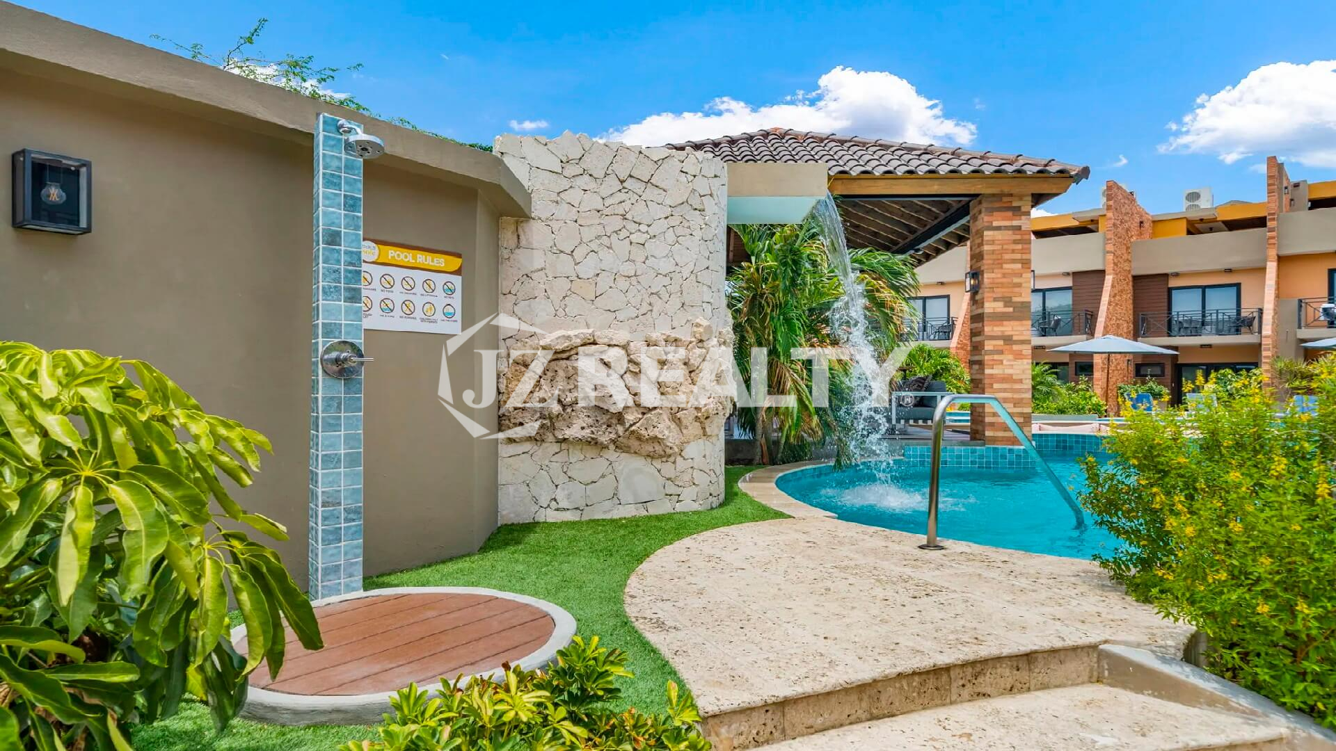 Outdoor pool shower station at Porta al Sole with a wooden platform and a stone accent wall next to the pool area.