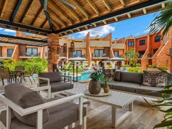 View of the poolside covered lounge and dining area (cabana) at Porta al Sole, showing comfortable outdoor sofas and tables overlooking the complex.