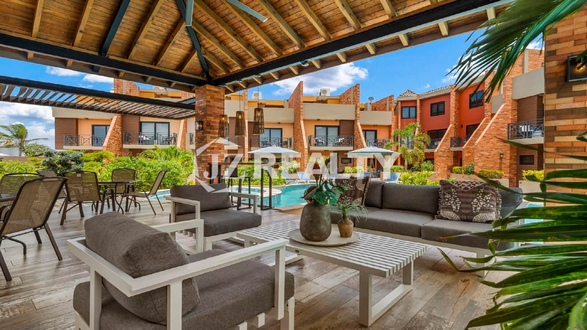 View of the poolside covered lounge and dining area (cabana) at Porta al Sole, showing comfortable outdoor sofas and tables overlooking the complex.