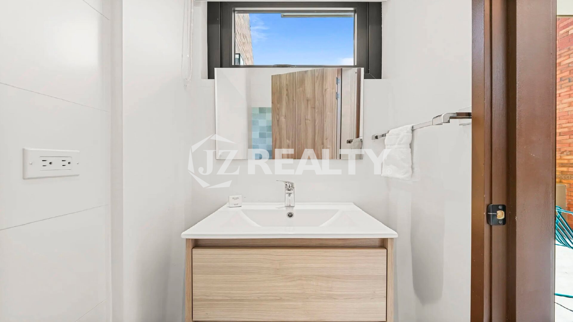 Ground floor half bathroom/powder room featuring a simple modern vanity with a light wood front and a window for natural light.