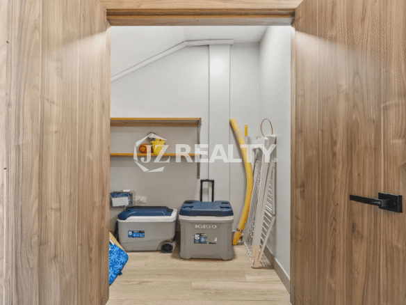 Utility closet with open doors, showing shelving and space for storing beach essentials like Igloo coolers and other supplies.