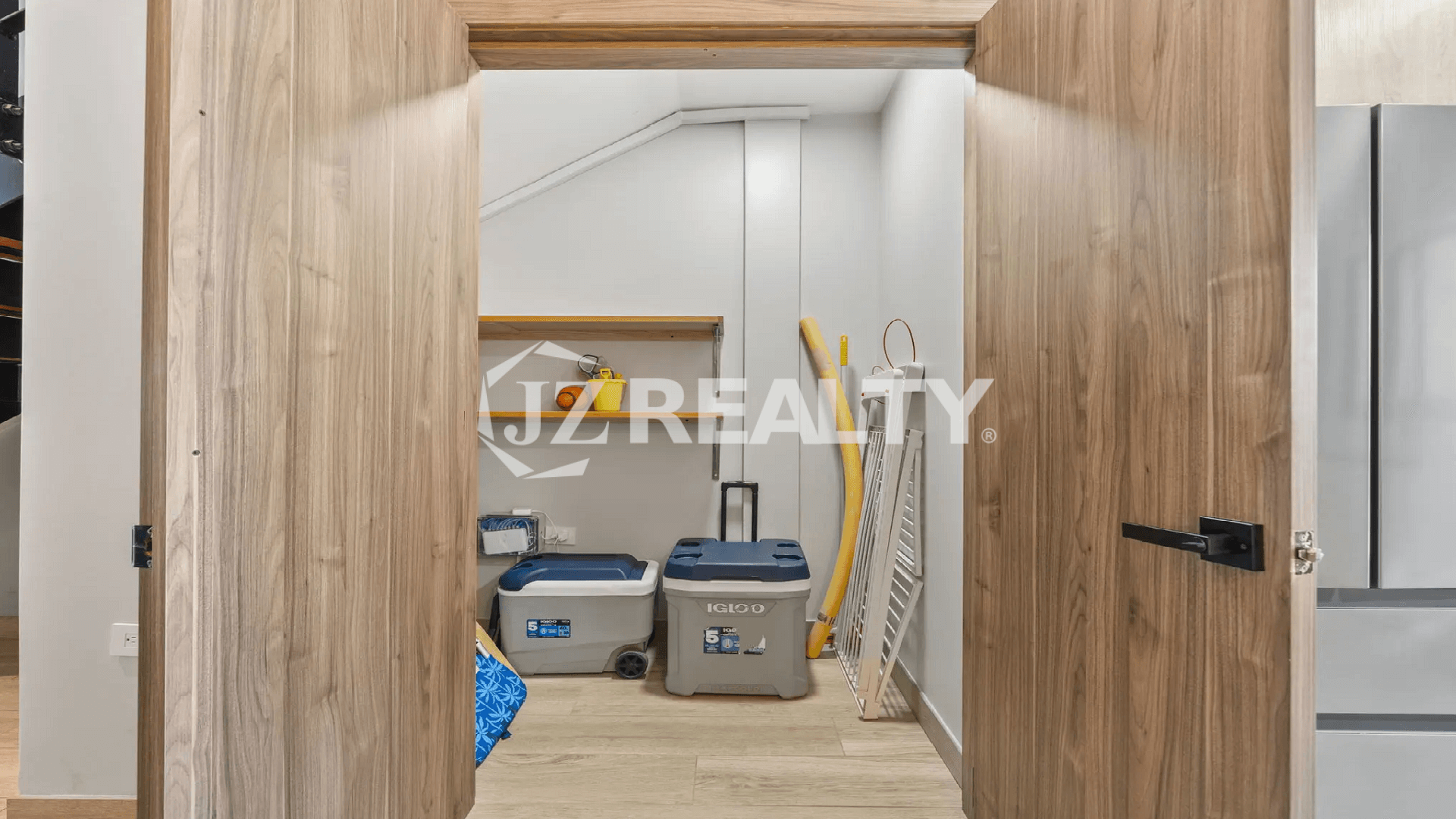 Utility closet with open doors, showing shelving and space for storing beach essentials like Igloo coolers and other supplies.
