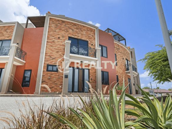 Exterior view of the Porta al Sole complex, highlighting Unit 13 with its orange stucco and brick facade, large glass doors, and balconies.