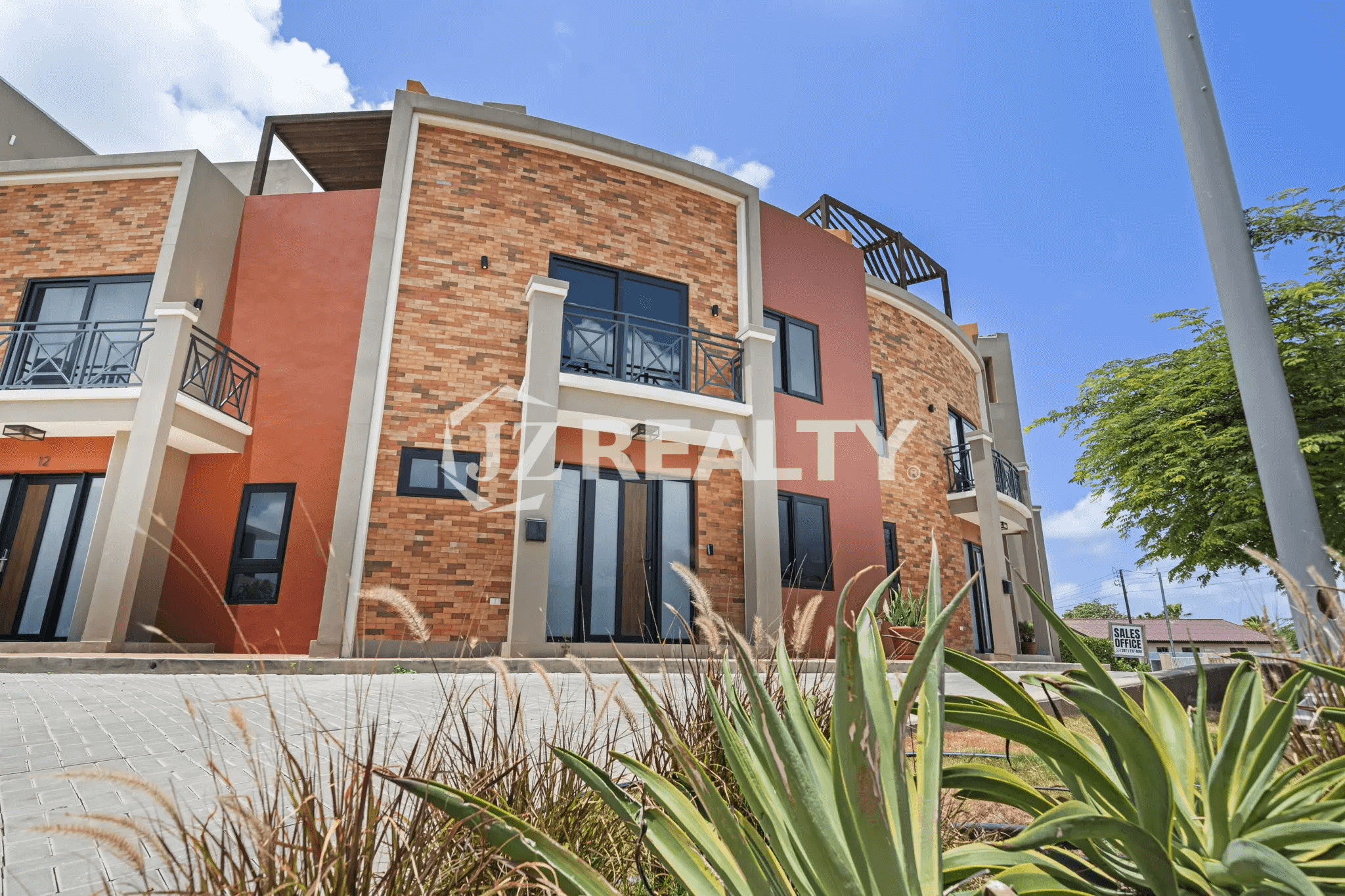 Exterior view of the Porta al Sole complex, highlighting Unit 13 with its orange stucco and brick facade, large glass doors, and balconies.