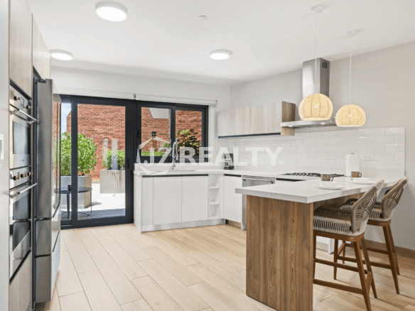 Modern white kitchen in Porta al Sole Unit 13 with light wood flooring, white countertops, stainless steel appliances, and island seating with woven stools.