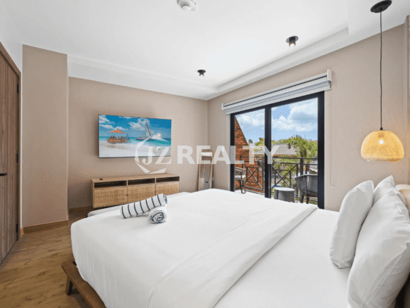Primary bedroom in Porta al Sole Unit 13 featuring a king bed, hardwood floor, TV, natural wood accents, and a glass door to a private balcony.