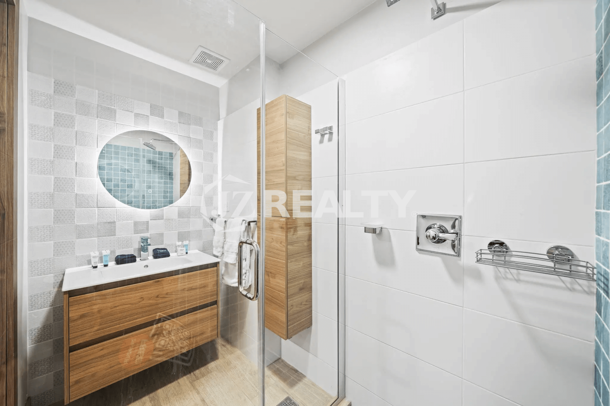 Stylish second bathroom in Porta al Sole Unit 13 with white wall tiles, wood-look vanity, mirror, and glass shower.