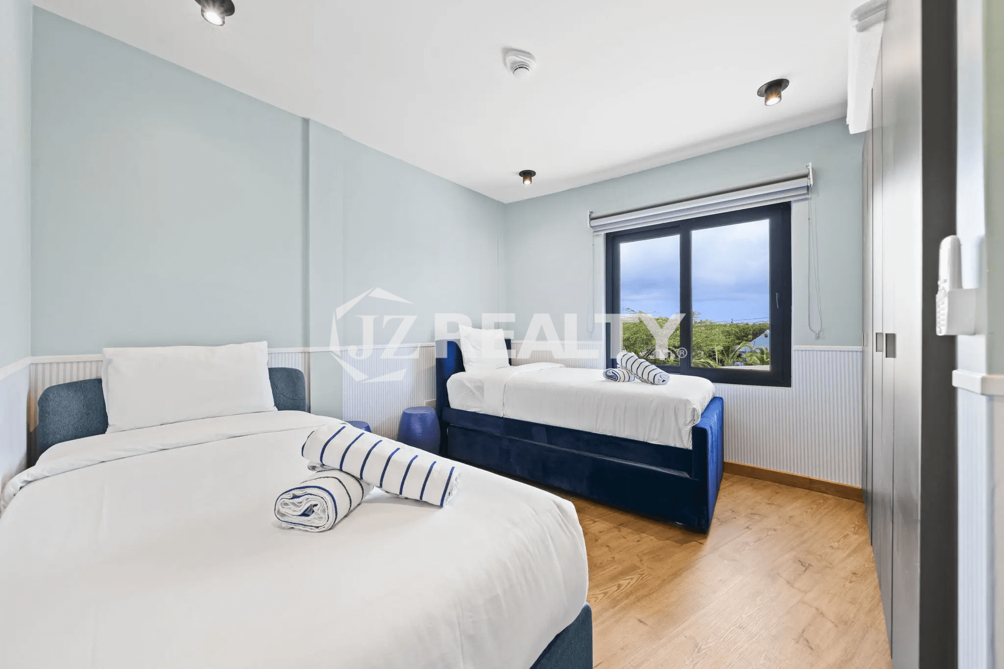 Second bedroom in Porta al Sole Unit 13 with light blue walls, two twin or day beds with blue velvet trim, and a window.