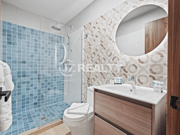 Contemporary bathroom with glass walk-in shower, blue mosaic tile, vanity, and round mirror in Porta al Sole Unit 14.