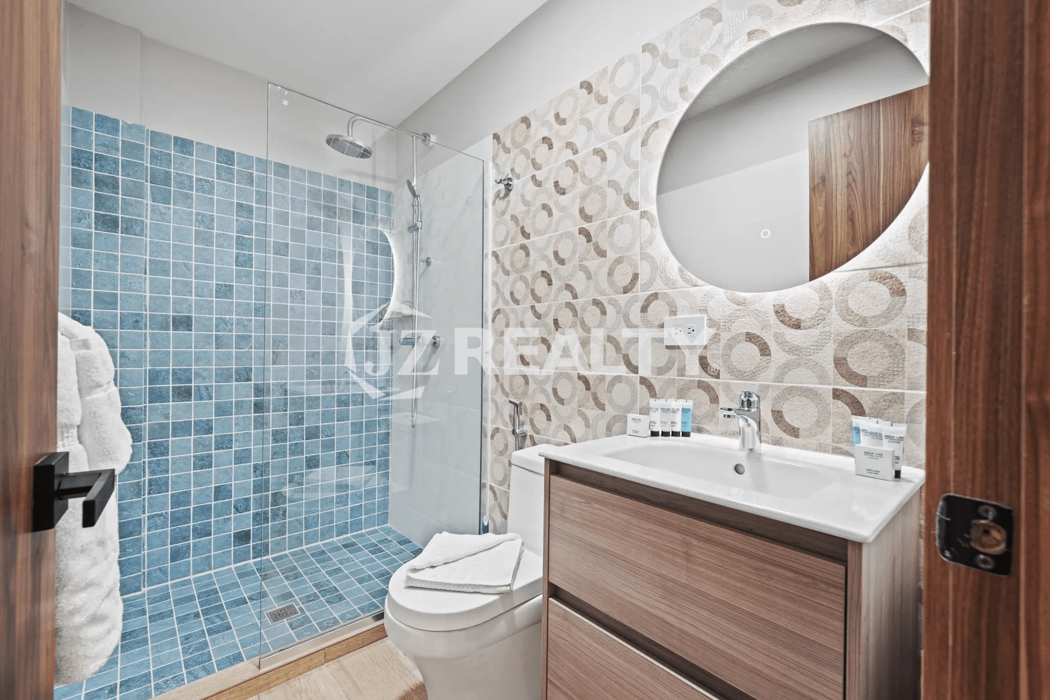 Contemporary bathroom with glass walk-in shower, blue mosaic tile, vanity, and round mirror in Porta al Sole Unit 14.
