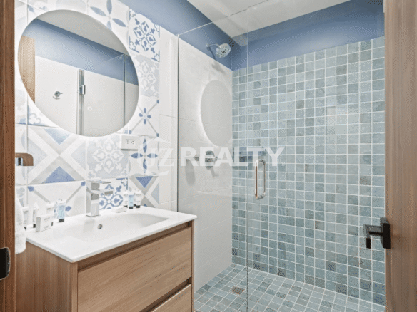 Second modern bathroom with wood vanity, round mirror, and walk-in shower with blue square and circular accent tiles in Porta al Sole Unit 14.