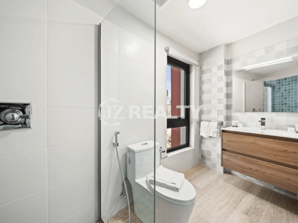 Third bathroom featuring a wooden vanity, square mirror, toilet with bidet spray, and large white tiles in Porta al Sole Unit 14.