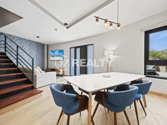Open-plan dining space with a white table, blue chairs, and modern staircase in Porta al Sole Unit 14.