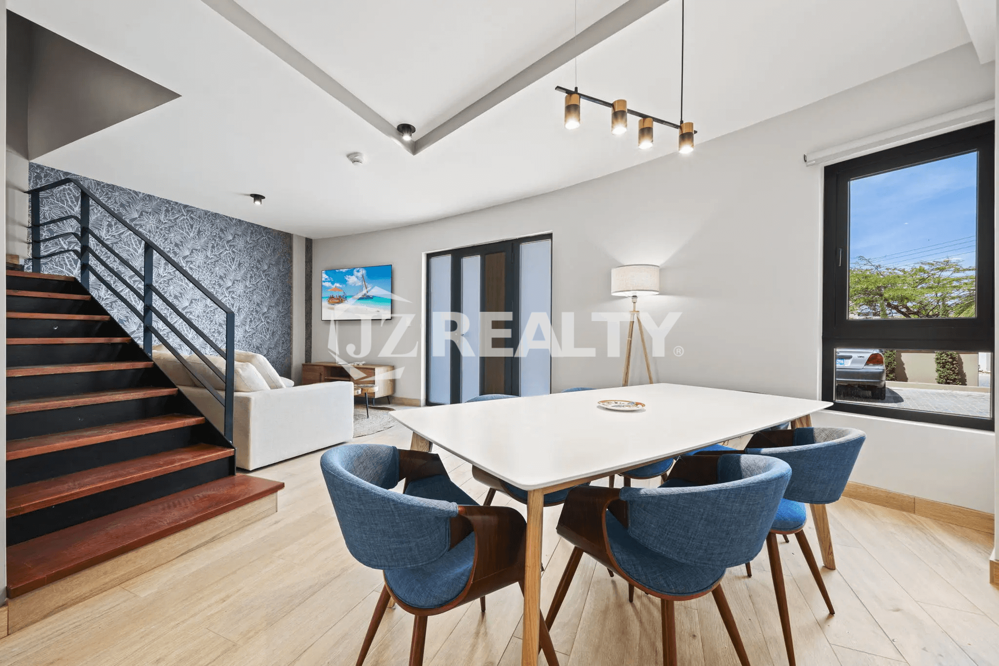 Open-plan dining space with a white table, blue chairs, and modern staircase in Porta al Sole Unit 14.