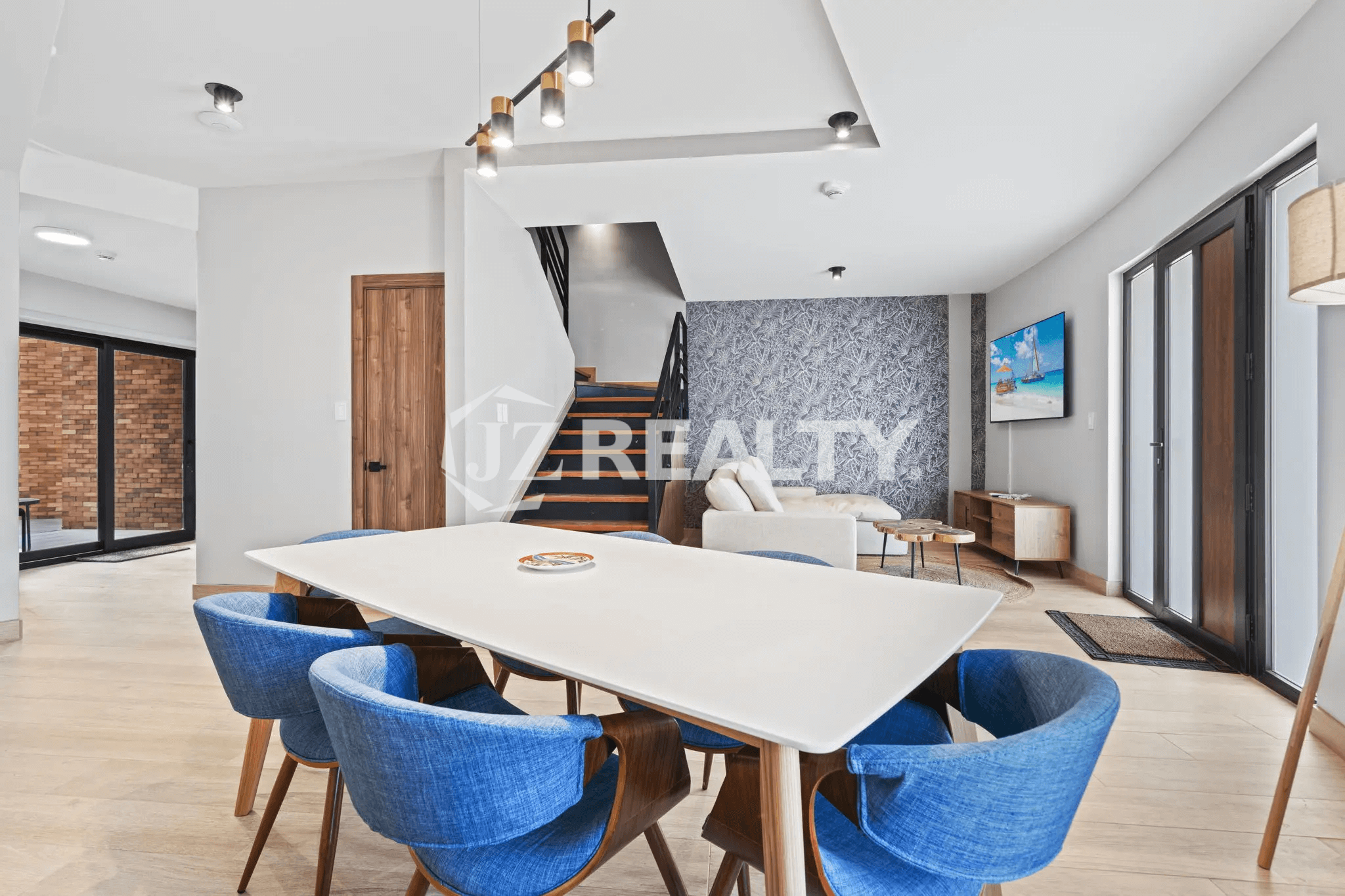 Open-concept living and dining area featuring a white table, blue dining chairs, and staircase in Porta al Sole Unit 14.