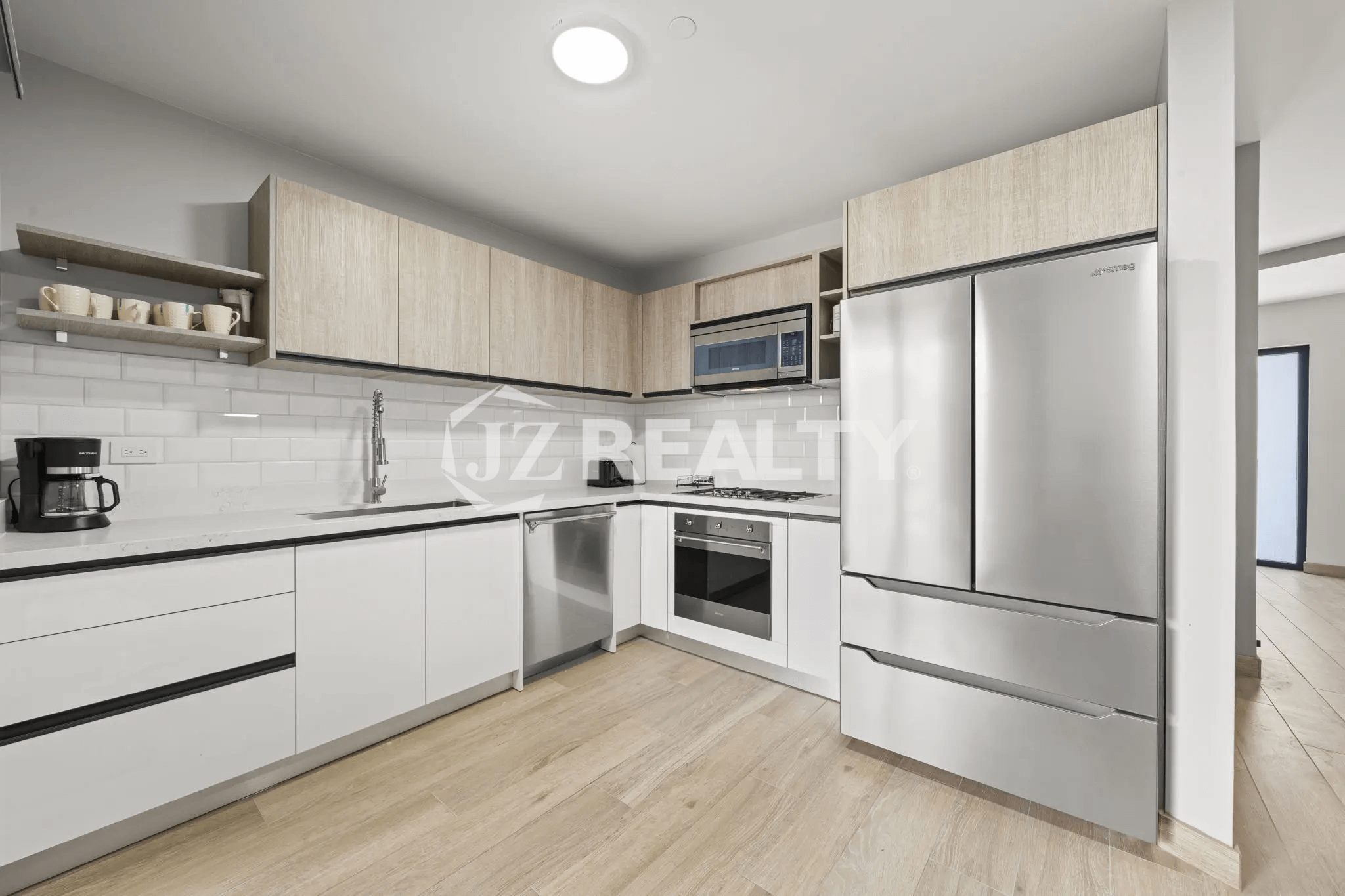 Fully-equipped modern kitchen with stainless steel Samsung refrigerator, oven, cooktop, and white subway tile backsplash in Porta al Sole Unit 14.