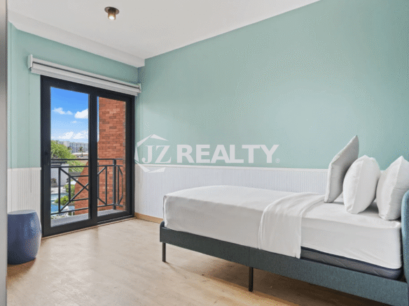 Guest bedroom with light blue walls, white wainscoting, and glass door access to an outdoor area in Porta al Sole Unit 14.
