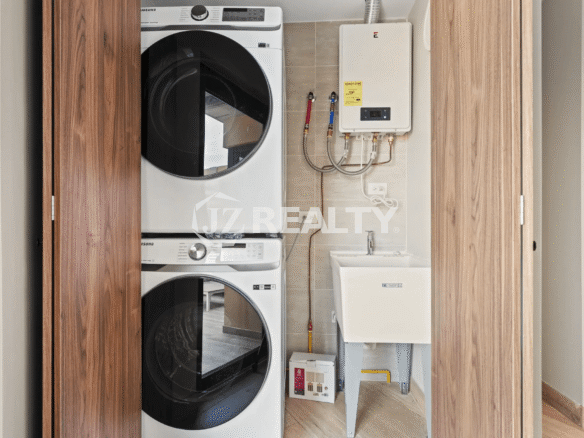 Stackable Samsung washer and dryer unit, utility sink, and water heater in the laundry closet of Porta al Sole Unit 14.