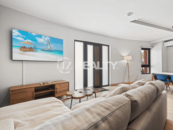 Modern living room with sectional sofa, wooden TV console, and flat-screen TV in Porta al Sole Unit 14.