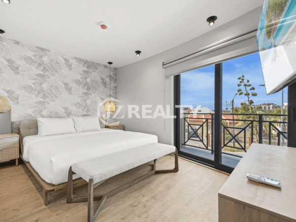 Spacious master bedroom with king-size bed, tropical accent wall, and glass door leading to a private balcony in Porta al Sole Unit 14.