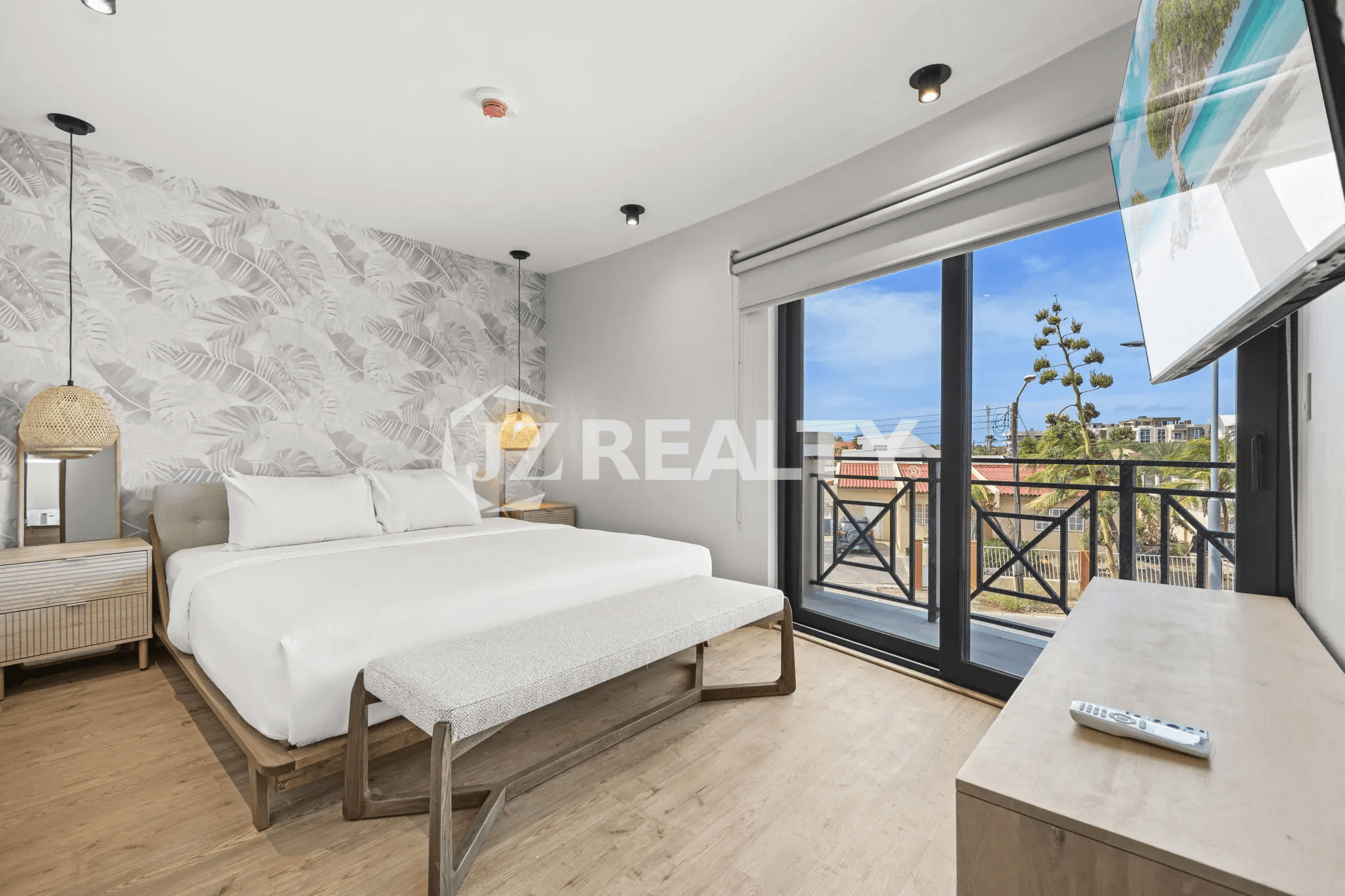 Spacious master bedroom with king-size bed, tropical accent wall, and glass door leading to a private balcony in Porta al Sole Unit 14.