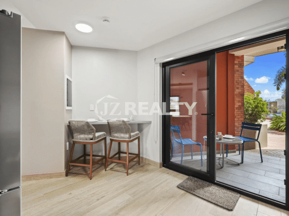 Indoor bar seating area adjacent to a sliding glass door leading to a small private patio in Porta al Sole Unit 14.
