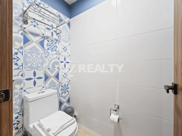 Stylish powder room with blue and white patterned accent tile wall and white toilet in Porta al Sole Unit 14.
