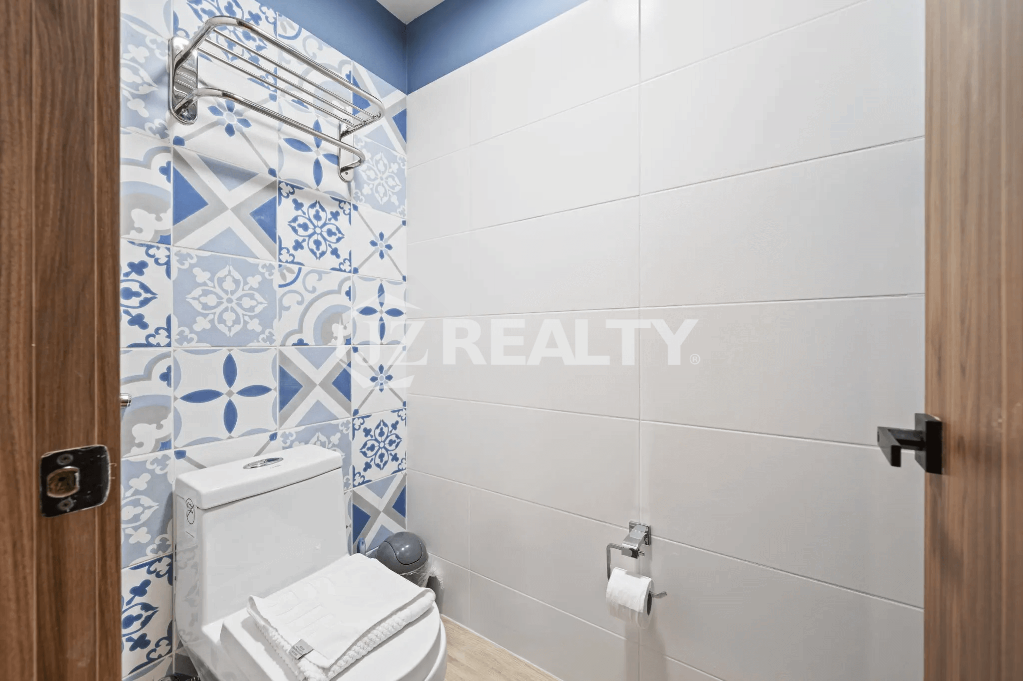 Stylish powder room with blue and white patterned accent tile wall and white toilet in Porta al Sole Unit 14.