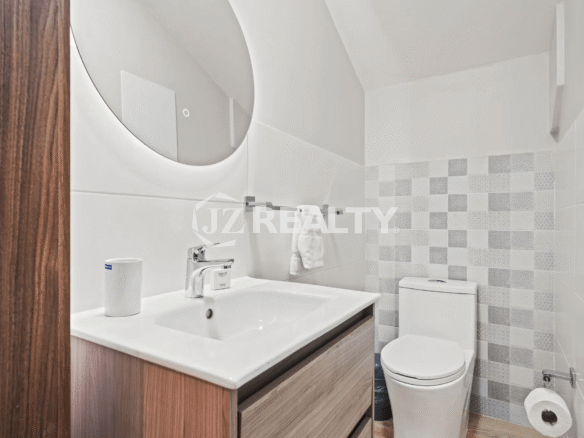 Modern powder room with a wood vanity, lighted circular mirror, and checkered accent tile wall in Porta al Sole Unit 14.