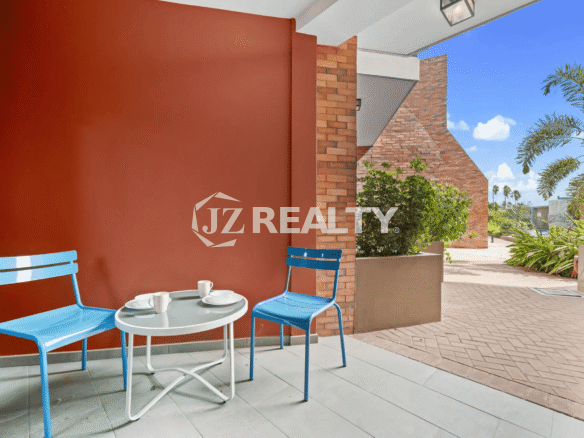Small outdoor patio with an accent brick wall and blue metal chairs with a small table in Porta al Sole Unit 14.