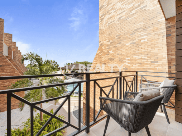 Balcony off the Primary or Guest Bedroom with black metal railing and two woven chairs, offering a view of the complex and surrounding landscape in Porta al Sole Unit 15.