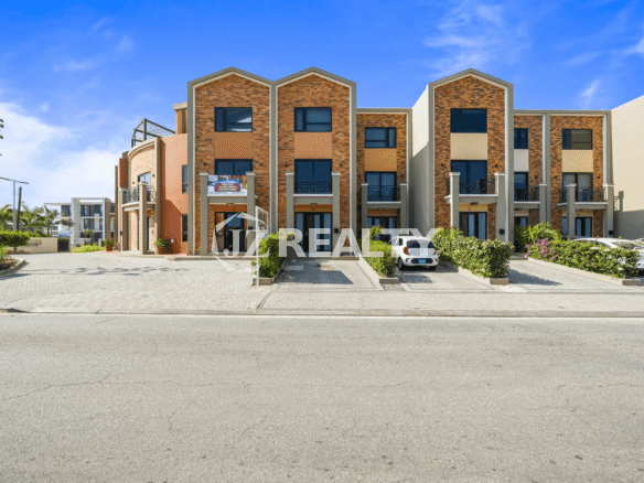Exterior street view of the modern, multi-story Porta al Sole complex with red brick accents and landscaping, showing the building entrance and front parking area.
