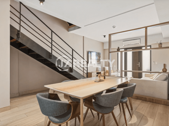 Dedicated dining area with a long light-wood table and gray upholstered chairs, located beneath the staircase, looking toward the living room in Porta al Sole Unit 15.