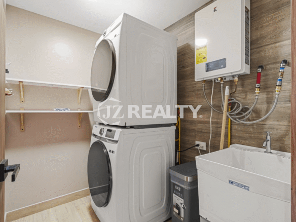 Dedicated laundry area with a stacked white washer and dryer unit, utility sink, and wall-mounted water heater in Porta al Sole Unit 15.