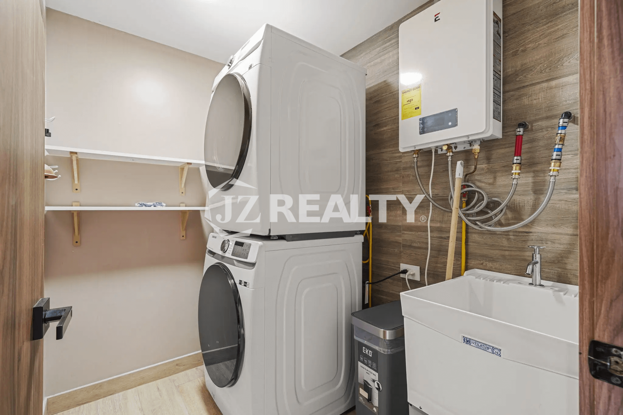Dedicated laundry area with a stacked white washer and dryer unit, utility sink, and wall-mounted water heater in Porta al Sole Unit 15.