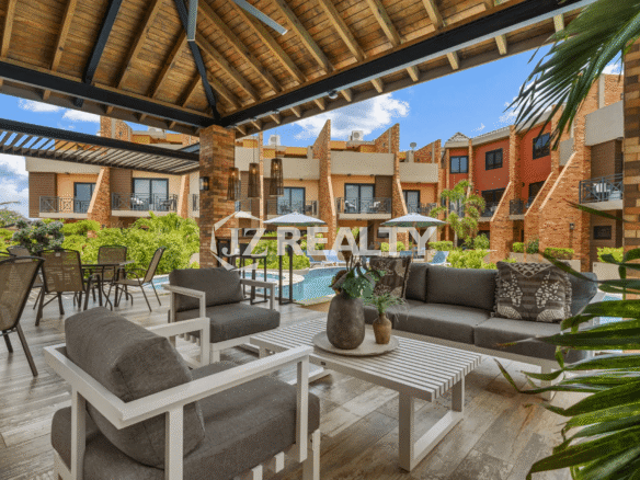 Interior view of the community's covered poolside cabana, furnished with comfortable outdoor lounge seating and dining sets, overlooking the pool and surrounding units.